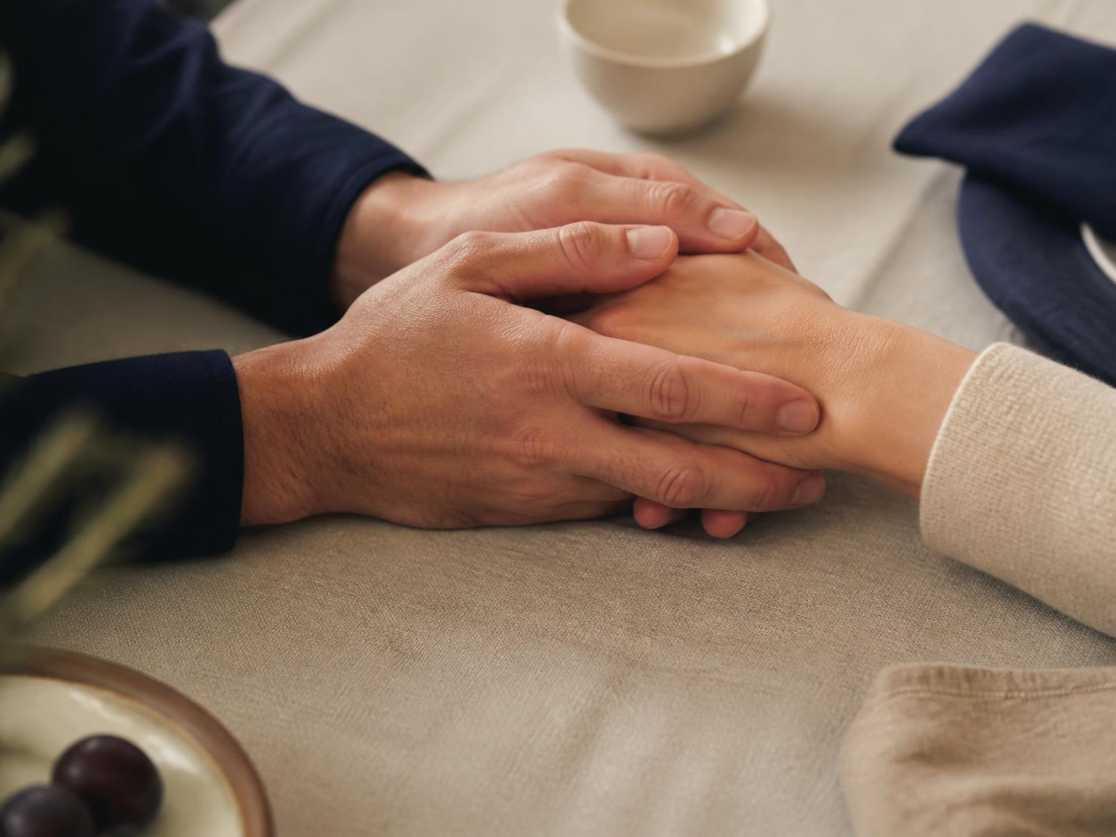 Dos manos adultas sostenidas con calma sobre una mesa